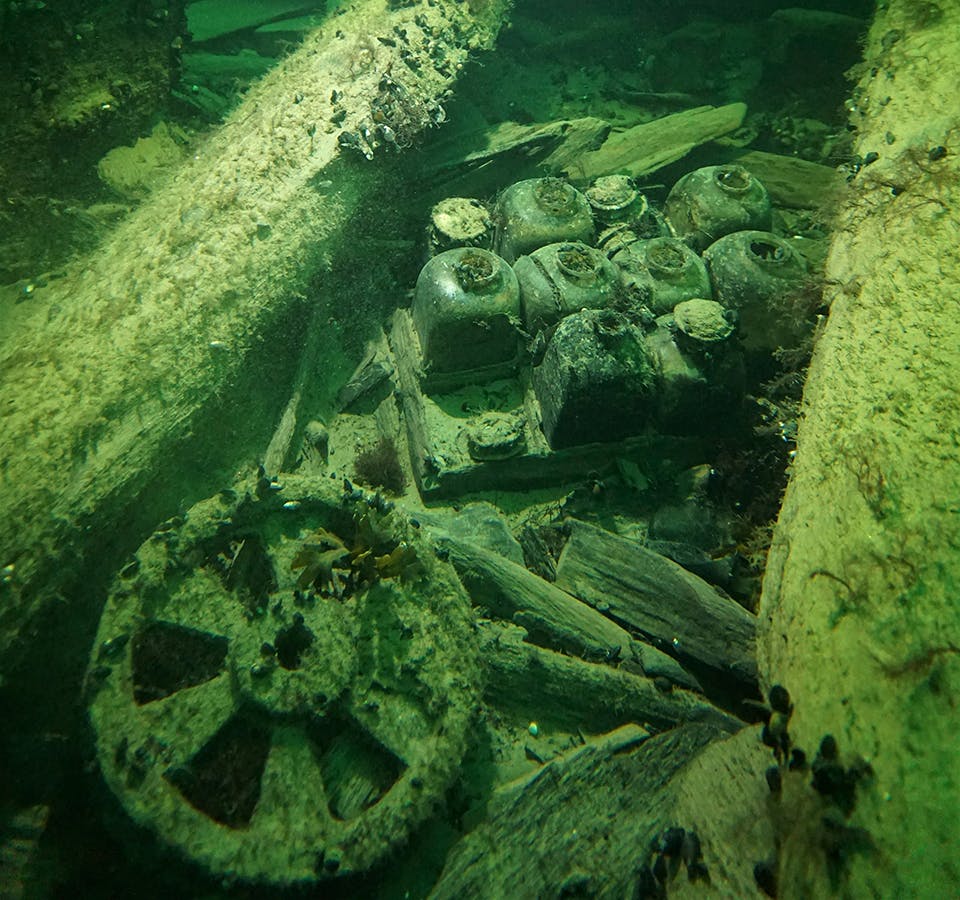 Här syns ett schatull i trä med flaskor och ett bronshjul som har använts till riggen. Här syns ett schatull i trä med flaskor och ett bronshjul som har använts till riggen.